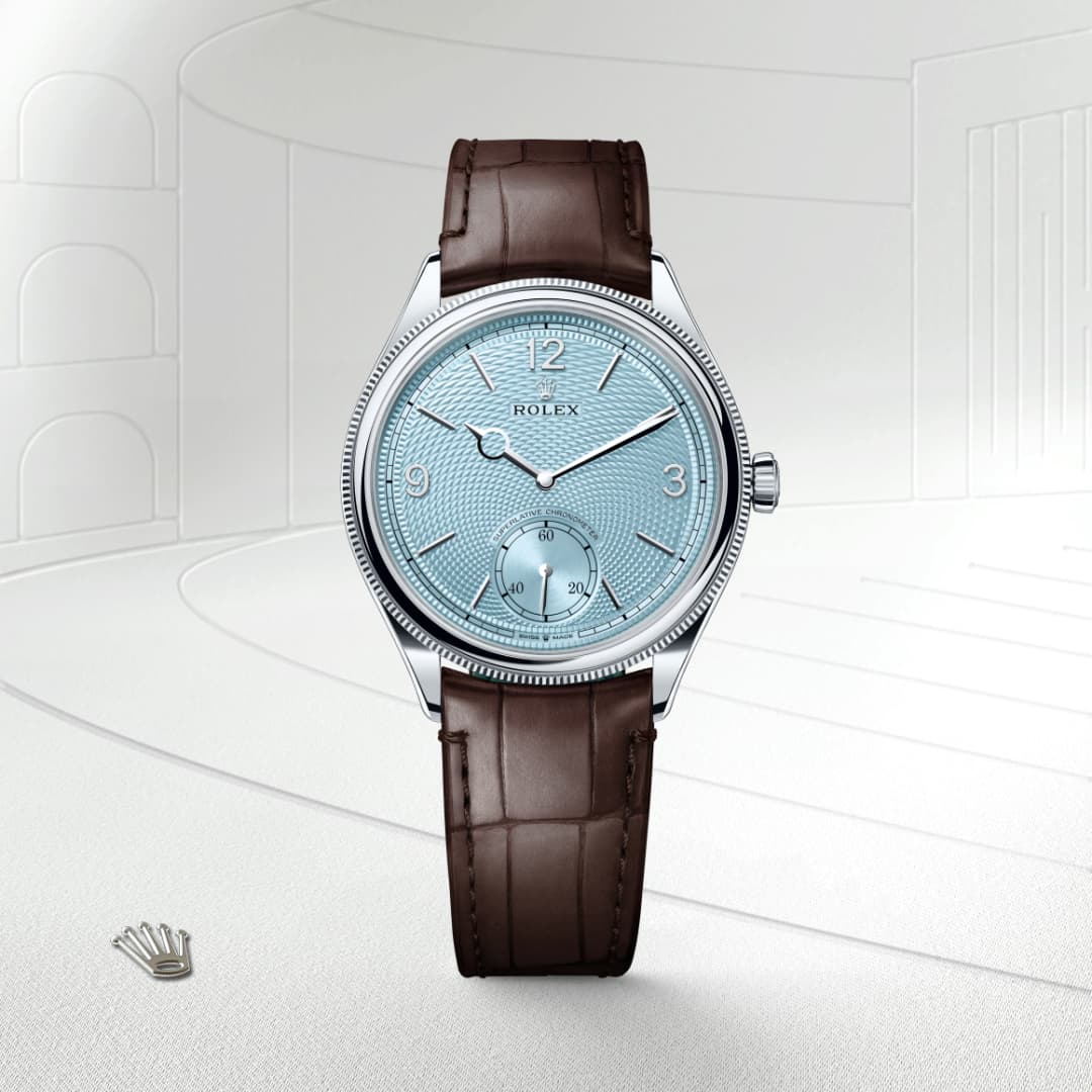 A Rolex wristwatch with a light blue dial and brown leather strap, displayed against a light, abstract background.