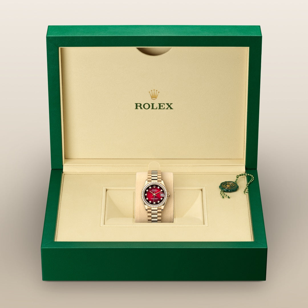 A Rolex watch with a red dial in a green and beige Rolex box, next to a green tag.