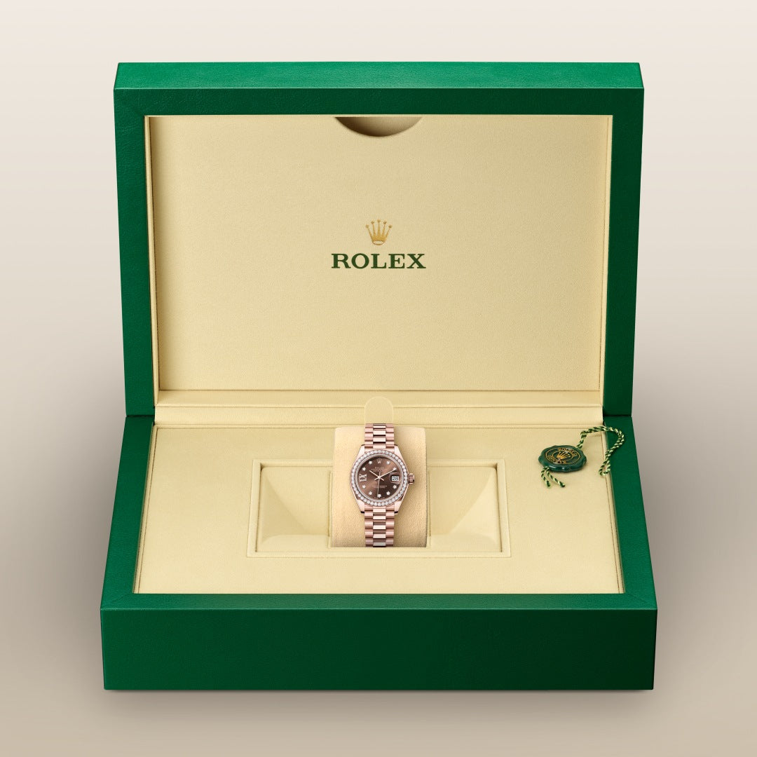A Rolex watch with a metal band displayed in an open green and beige Rolex box.