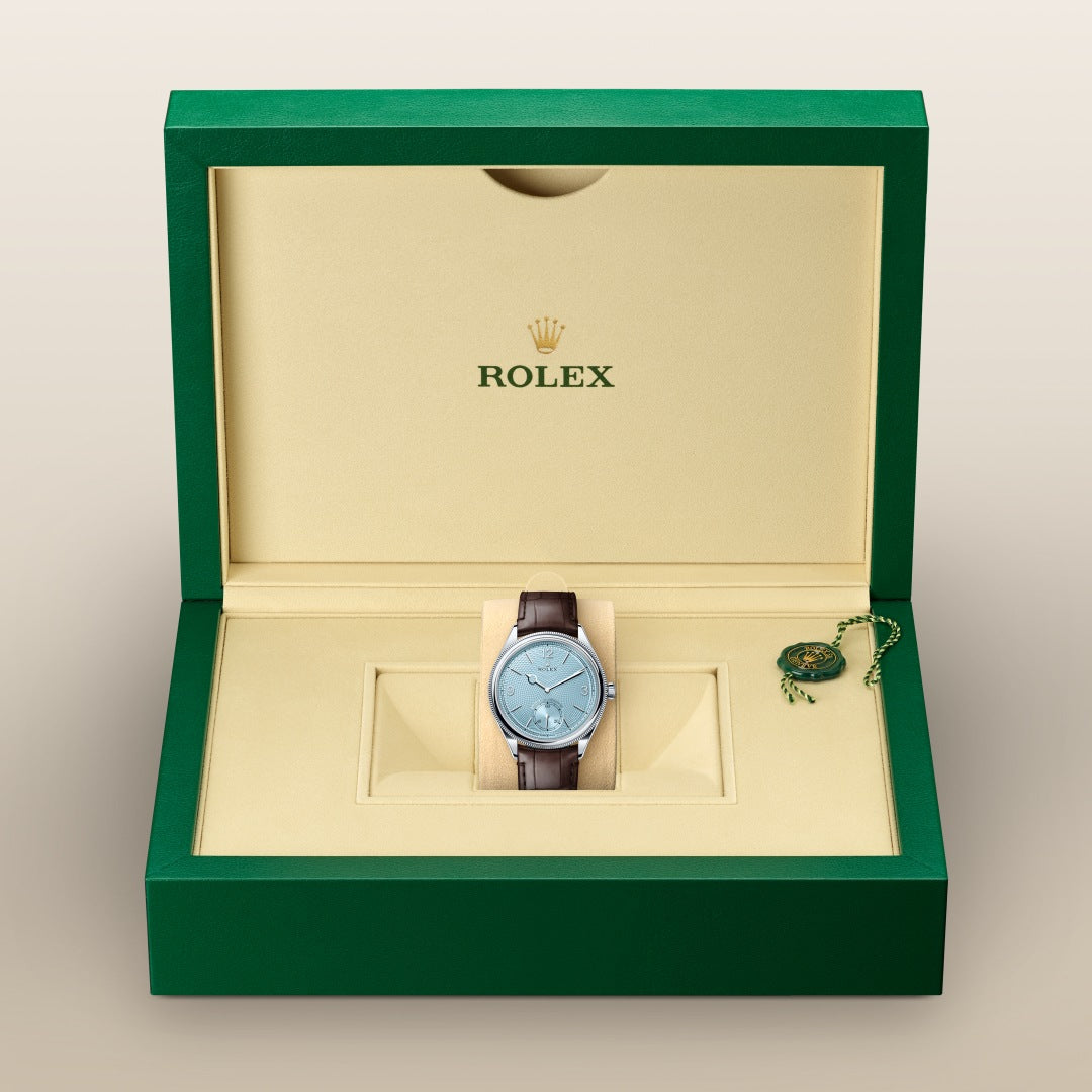 A Rolex watch with a brown leather strap in a green and beige Rolex box.