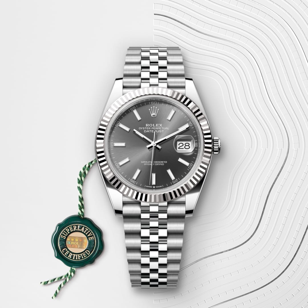 Silver Rolex Datejust watch with a grey dial and Jubilee bracelet, next to a green Superlative Certified tag.