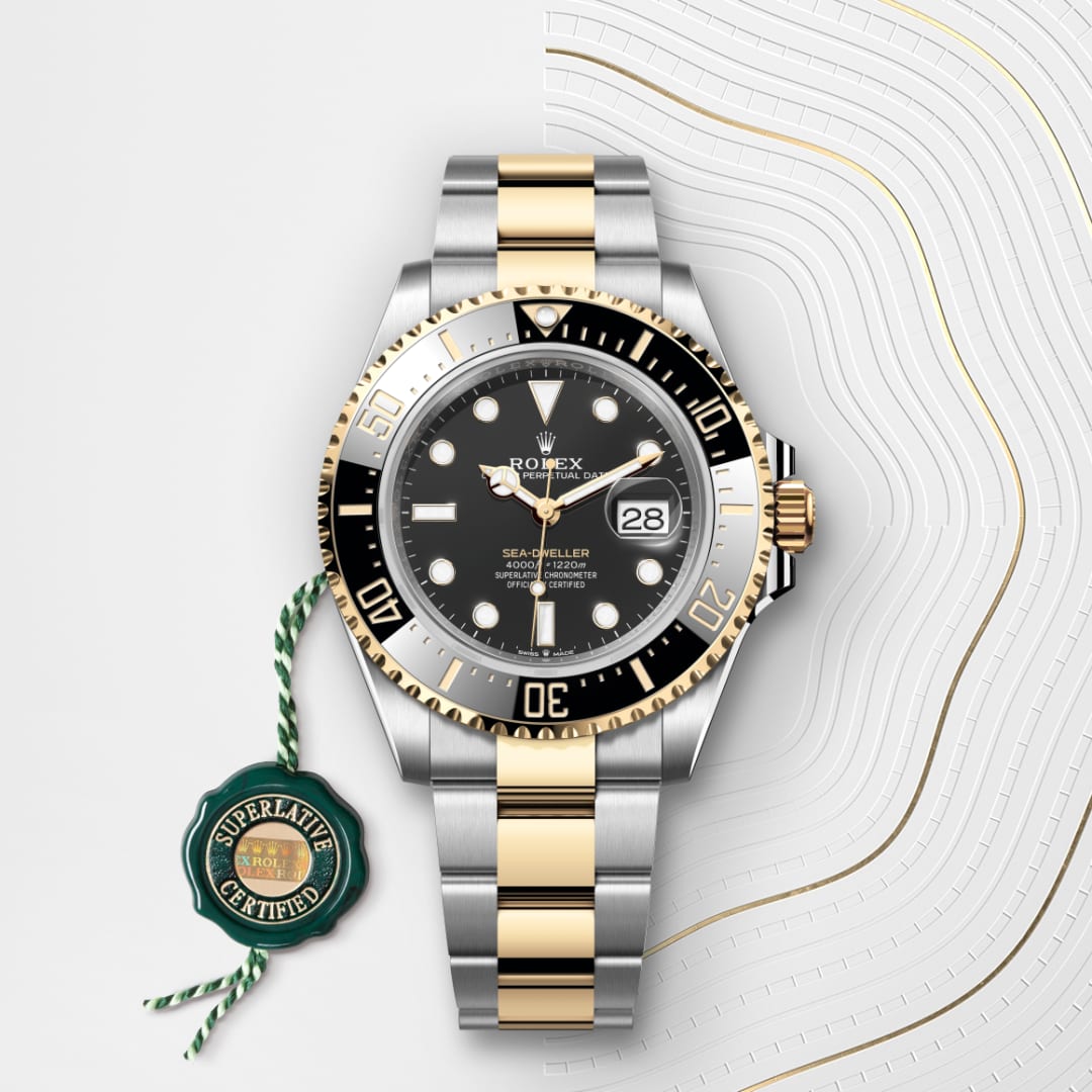 A two-tone Rolex Sea-Dweller watch with a black dial and a green Superlative Certified tag beside it.