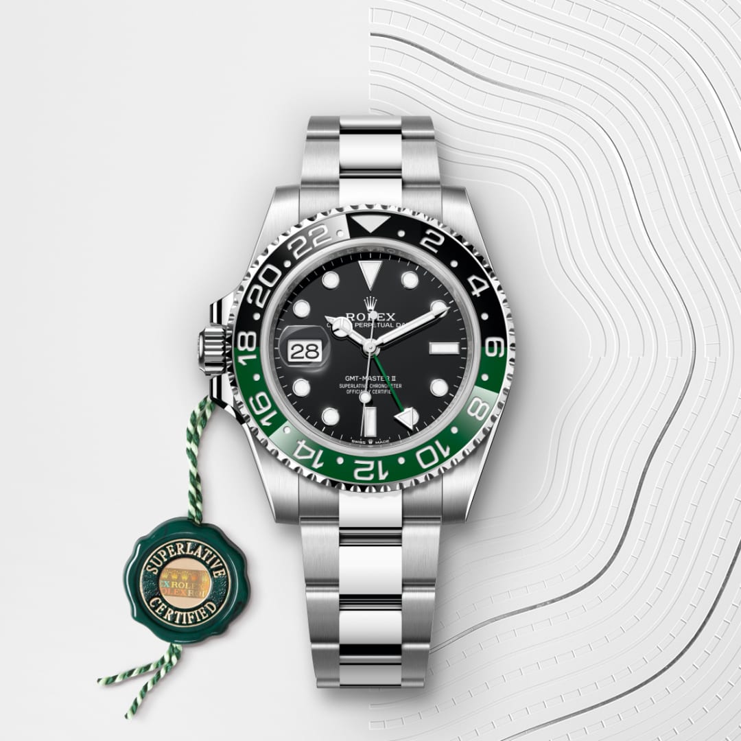 A silver Rolex watch with a green and black bezel, date display, and Superlative Certified tag.