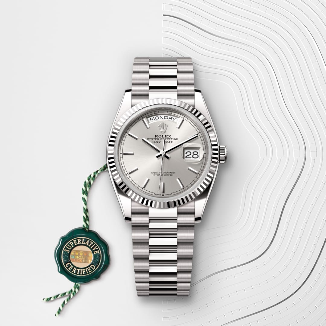 Silver Rolex watch with a fluted bezel, day and date display, and a green Superlative Certified tag.