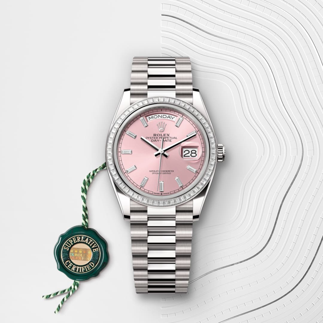 A silver Rolex watch with a pink dial and date display, beside a green Superlative Certified tag.