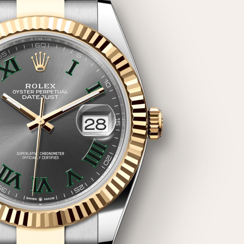 Close-up of a Rolex Datejust watch with a gold bezel, silver dial, green Roman numerals, and date displayed at 3 o’clock.