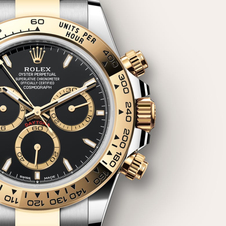 Close-up of a Rolex Daytona watch with a black dial and gold bezel, showcasing chronograph subdials.