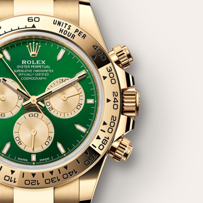 Close-up of a gold Rolex watch with a green face and three subdials, showing detailed craftsmanship.
