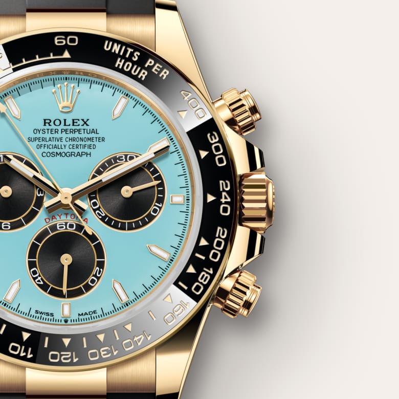 Close-up of a Rolex Daytona watch with a gold case, black bezel, and light blue dial.