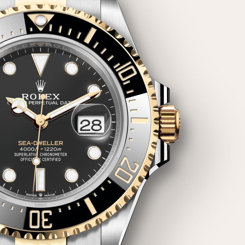 Close-up of a Rolex Sea-Dweller watch showing the black and gold bezel, dial, and date display.
