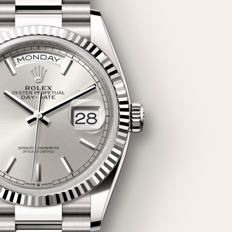 Close-up of a silver Rolex Day-Date watch showing Monday and the 28th on its dial.