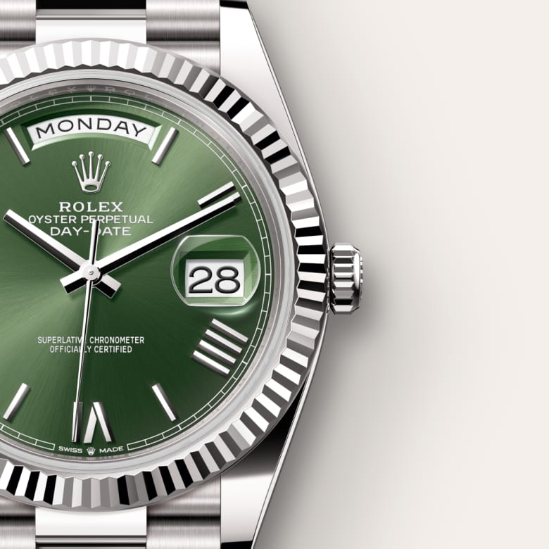 Close-up of a Rolex watch with a green dial, showing the day (Monday) and date (28) displays.