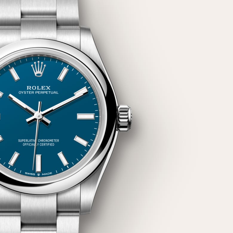 Close-up of a Rolex Oyster Perpetual watch with a blue dial and silver metal strap on a light background.