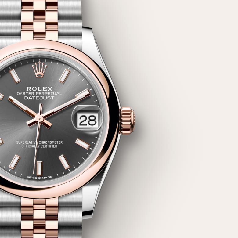 Close-up of a Rolex Datejust watch with rose gold and silver band, grey dial, and date display set to the 28th.