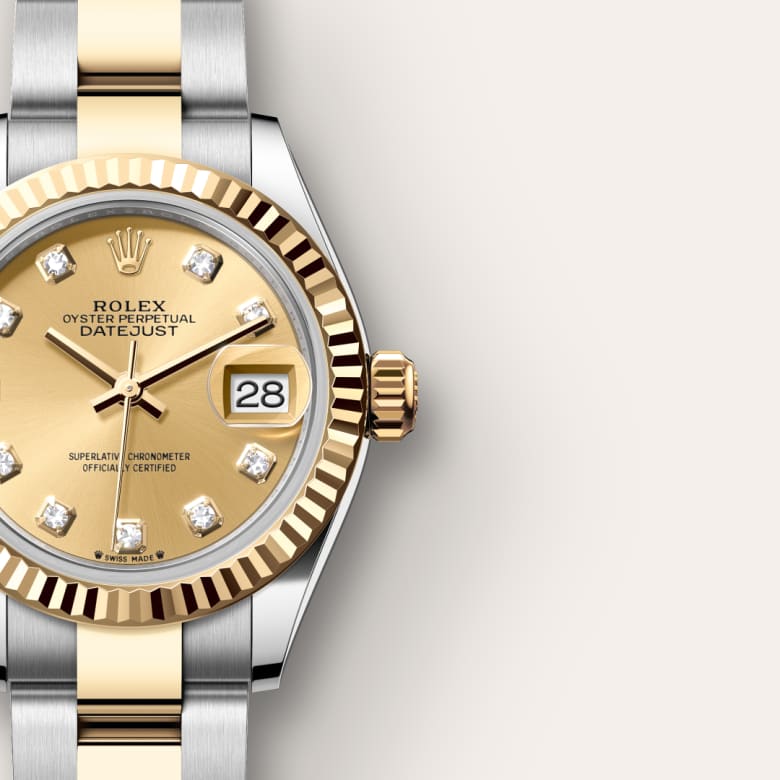 Close-up of a gold and silver Rolex watch showing diamond hour markers and the date window displaying 28.