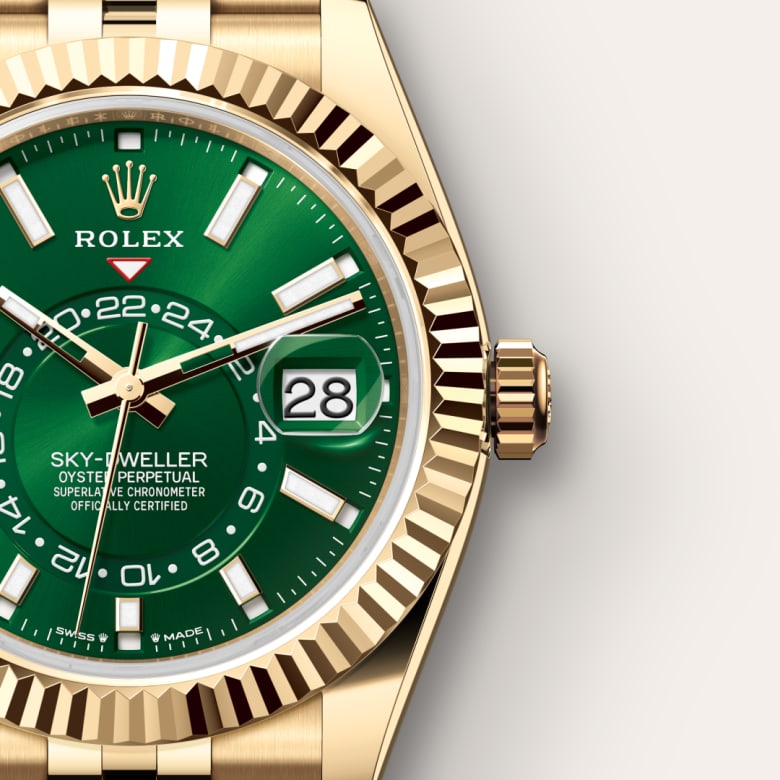 Gold Rolex Sky-Dweller watch with green dial, date window, and fluted bezel on a neutral background.