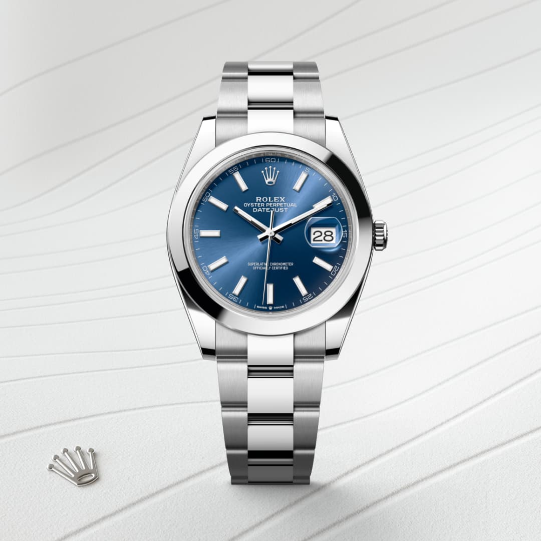 Silver Rolex watch with a blue dial and date display, placed on a textured white surface.