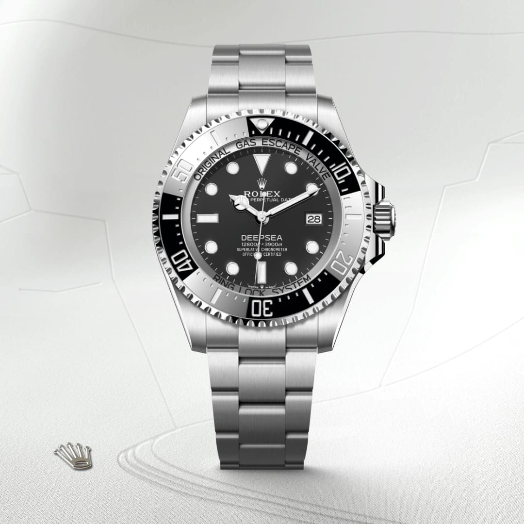 Silver Rolex Deepsea watch with a black dial and metal bracelet on a light textured background.