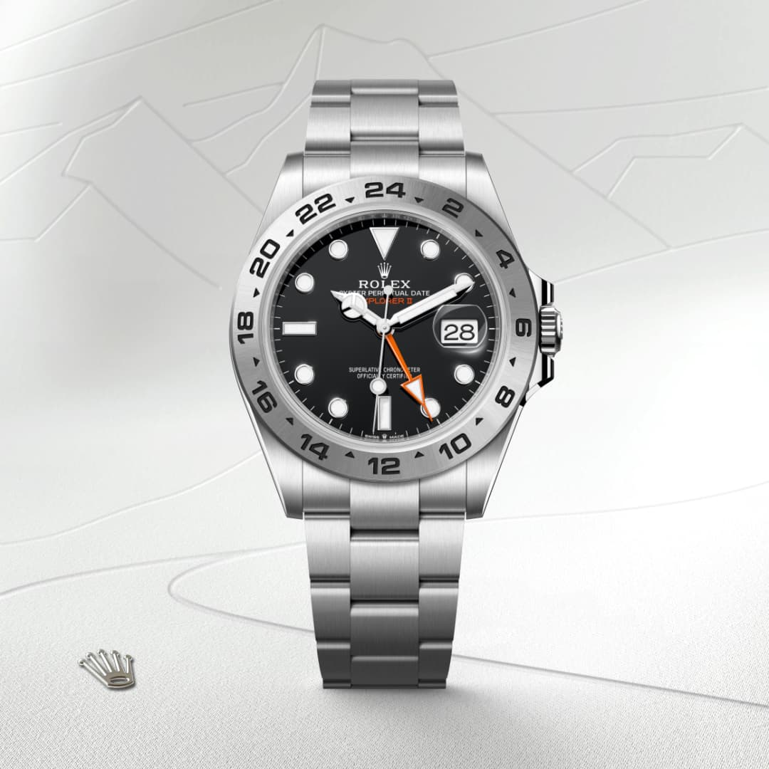 Silver Rolex Explorer II watch with a black dial and orange hand, displayed on a light textured surface.
