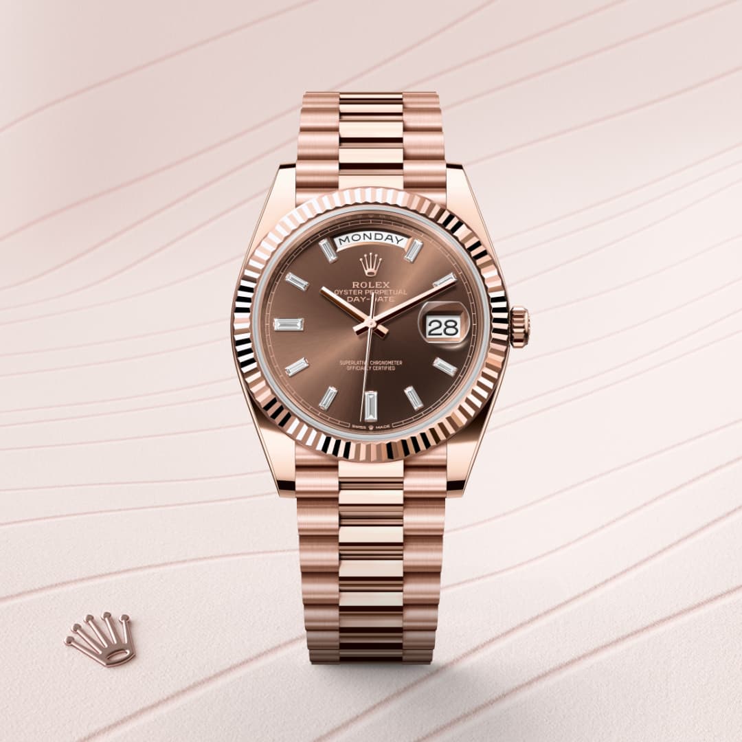 A rose gold Rolex watch displays the day and date on a textured light pink background.