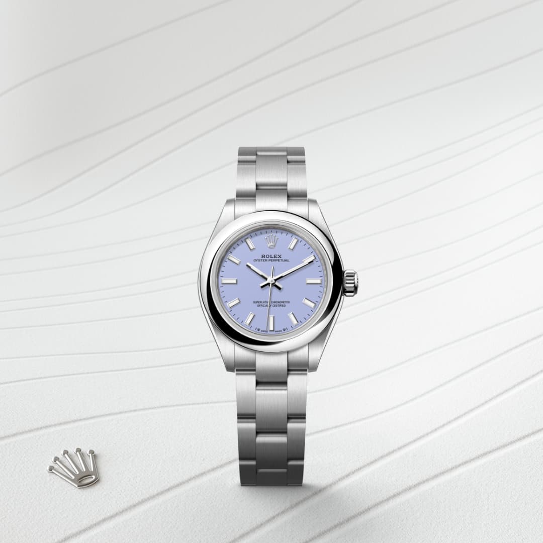 A silver Rolex watch with a light blue face on a textured white surface, next to a small Rolex crown logo.