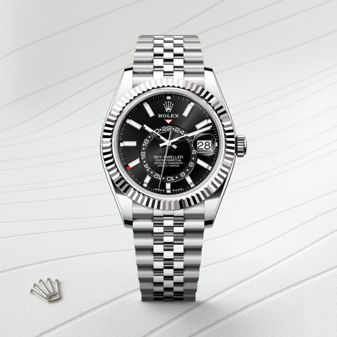A silver Rolex Sky-Dweller watch with a black dial on a textured white surface.