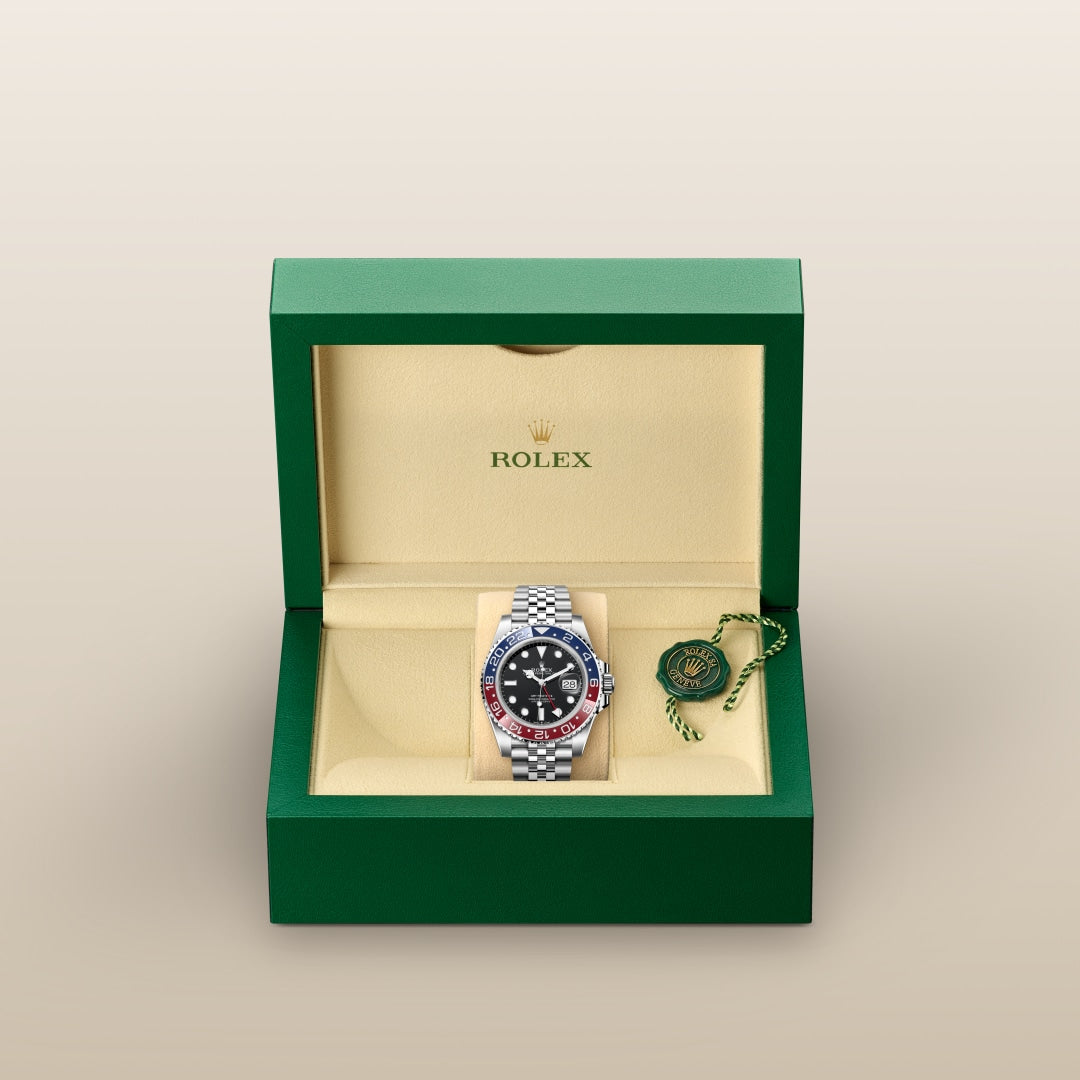 A Rolex watch with a red and blue bezel in a green and beige Rolex box with a green tag.
