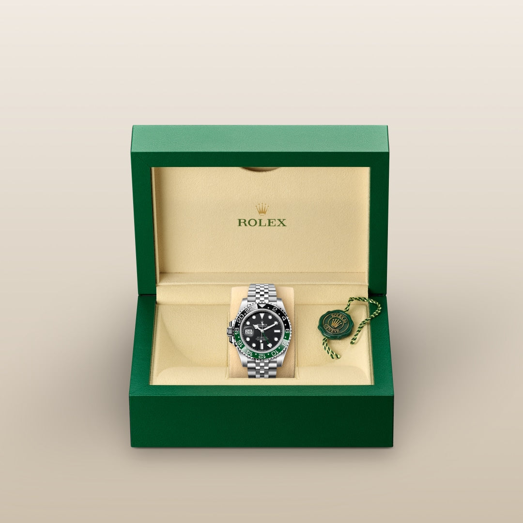 A Rolex watch with a green and black bezel in a green and beige presentation box with a tag.