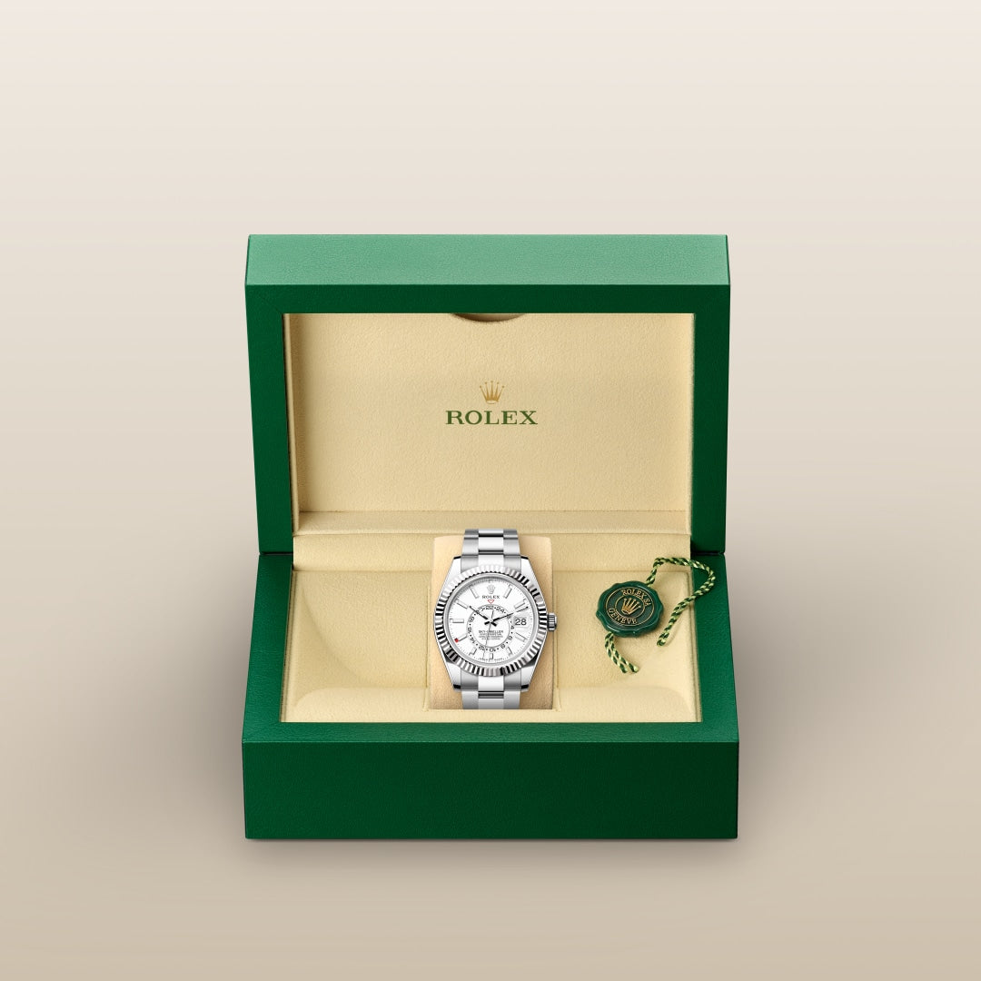 A silver Rolex watch in a green and beige box with a Rolex tag beside it.