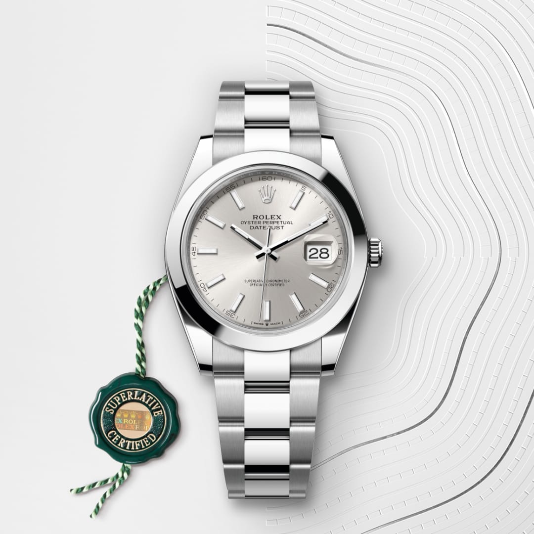 Silver Rolex Datejust watch with a silver dial and date display, next to a green “Superlative Certified” tag.