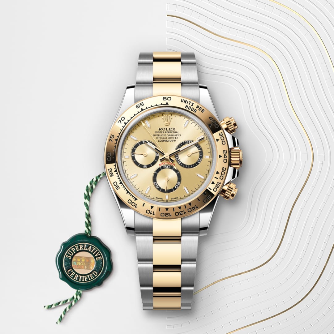 A gold and silver Rolex watch with three subdials, beside a green Superlative Certified tag.