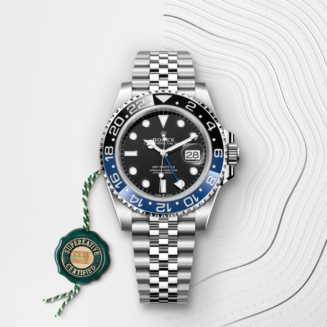 A Rolex GMT-Master II watch with a black and blue bezel on a silver bracelet, shown with a certification tag.