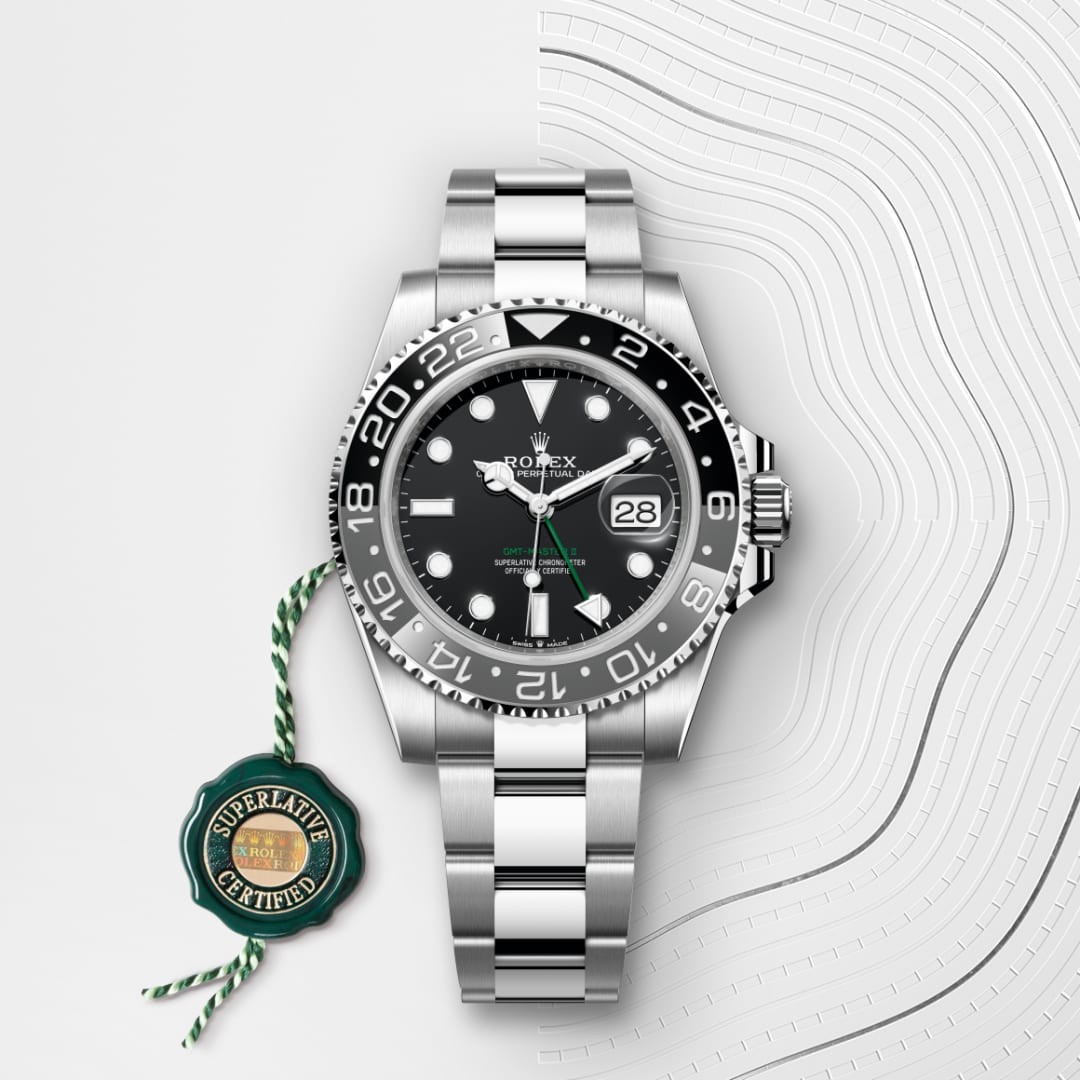 A silver Rolex watch with a black dial and date display, next to a green “Superlative Certified” tag.