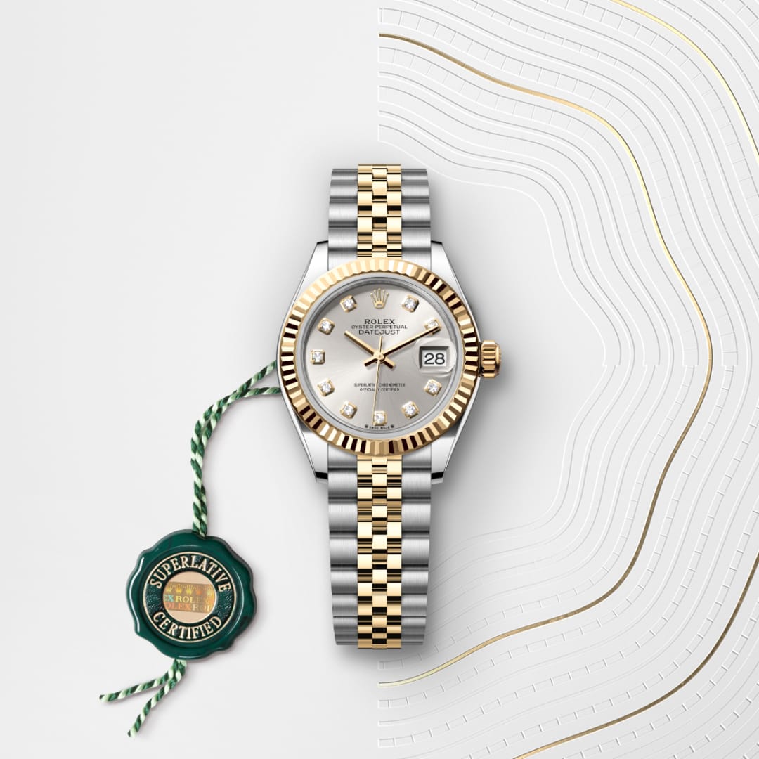 A two-tone Rolex watch with a silver dial, gold bezel, and Jubilee bracelet, next to a green Superlative Certified tag.
