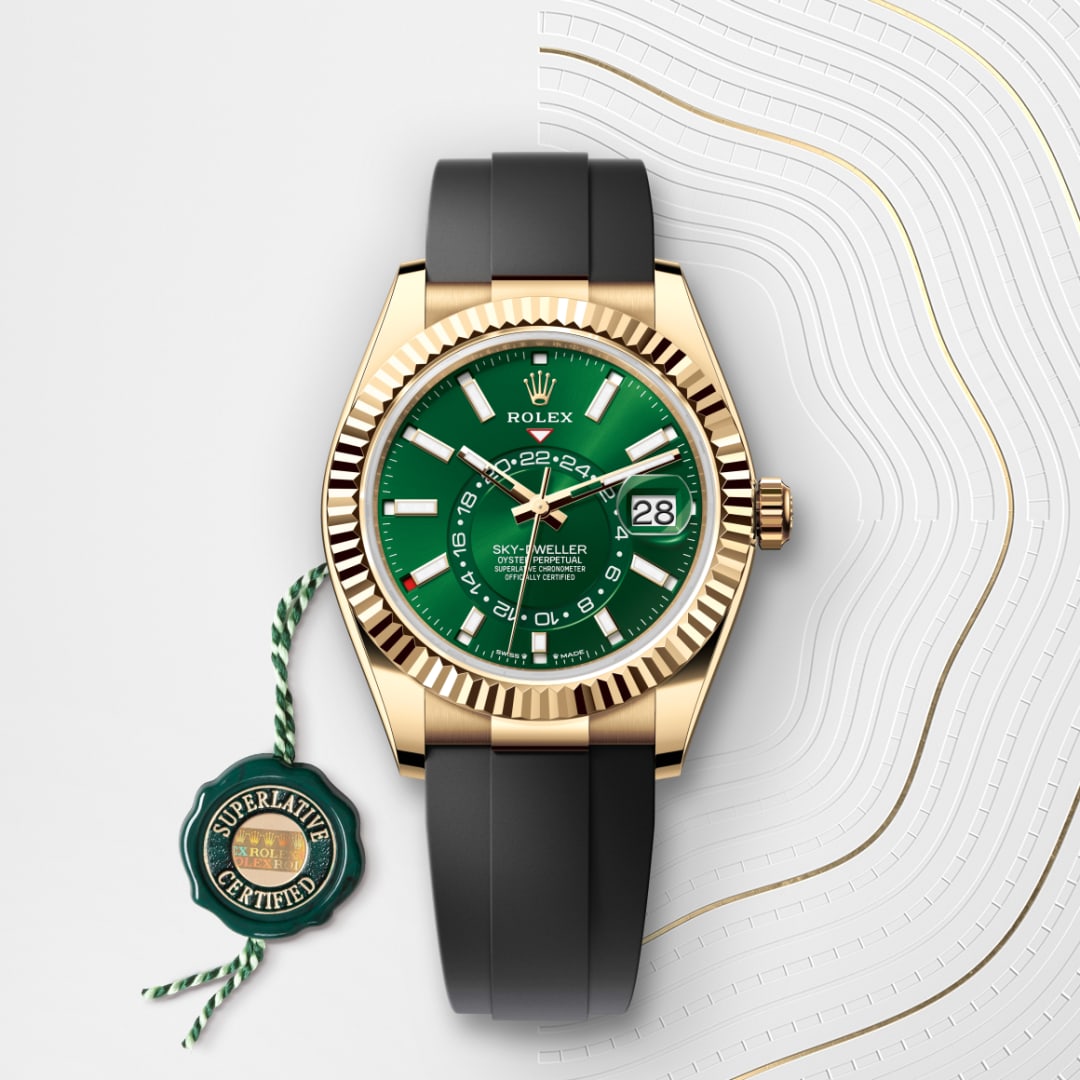 A gold Rolex Sky-Dweller with a green dial and black strap, placed beside a green Superlative Certified tag.