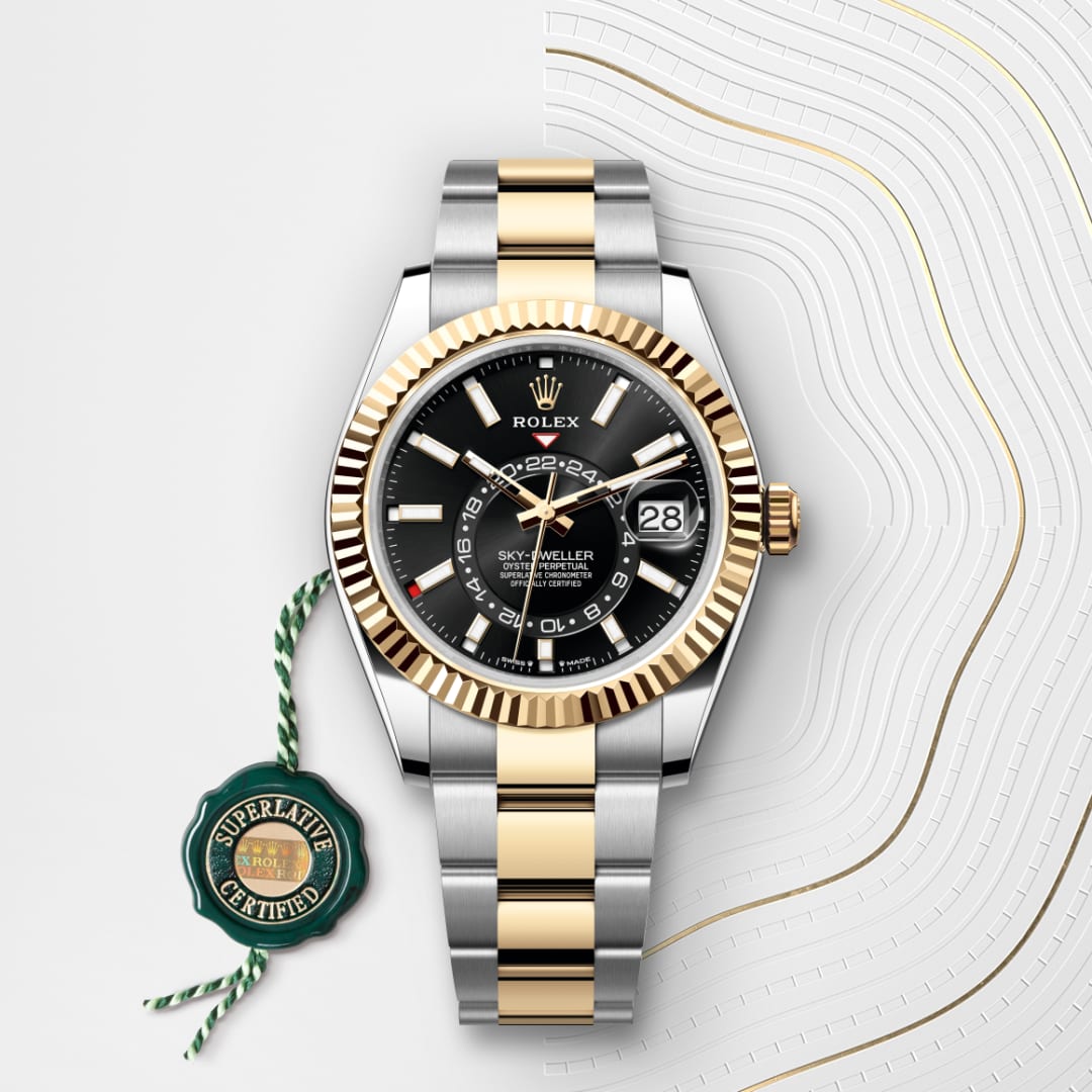 A two-tone Rolex Sky-Dweller watch with a black dial and gold accents, beside a green certification tag.