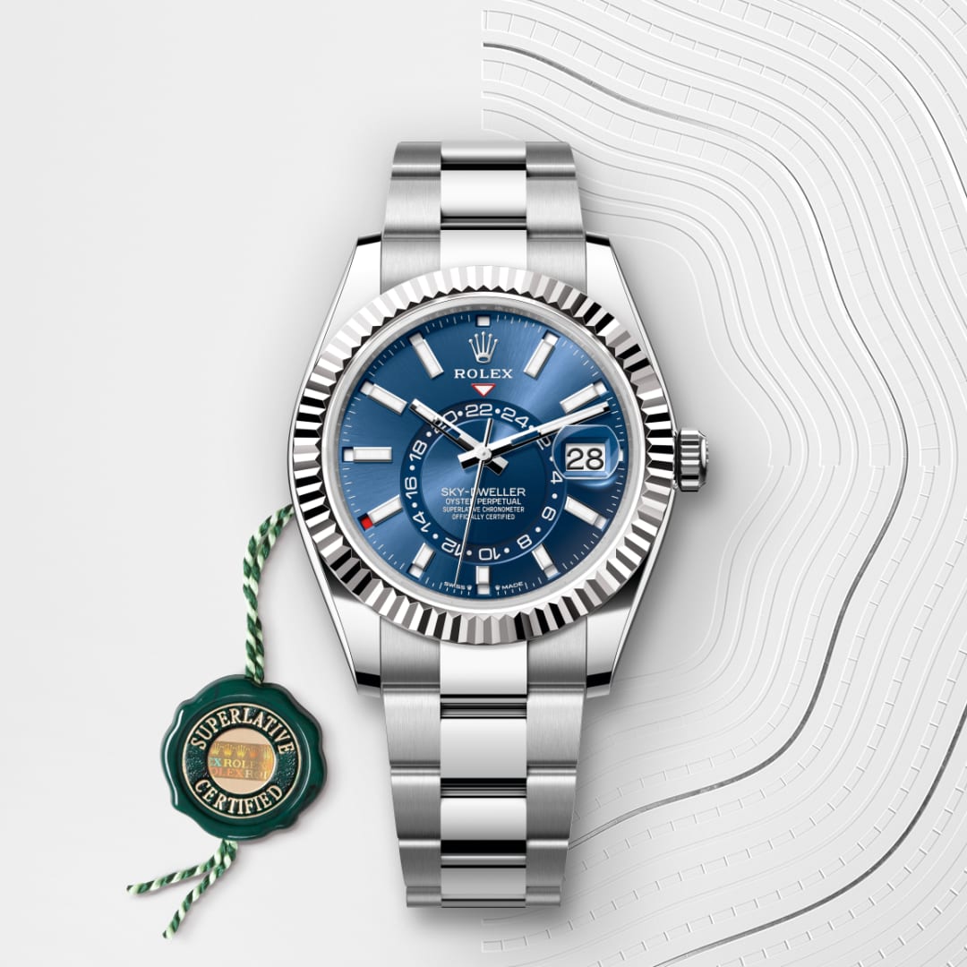 A stainless steel Rolex Sky-Dweller watch with a blue dial and date display, next to a green certification tag.