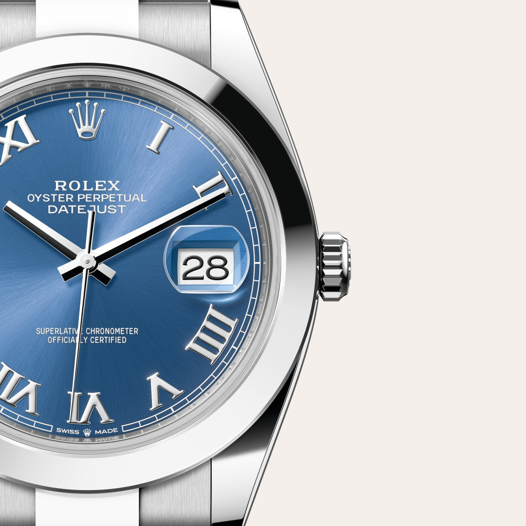 Close-up of a Rolex Datejust watch with a blue dial, Roman numerals, and a date display showing the 28th.
