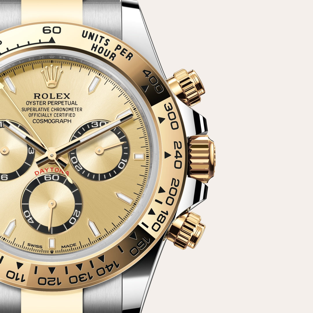 Close-up of a gold and silver Rolex Daytona watch face showing three black subdials and detailed markings.