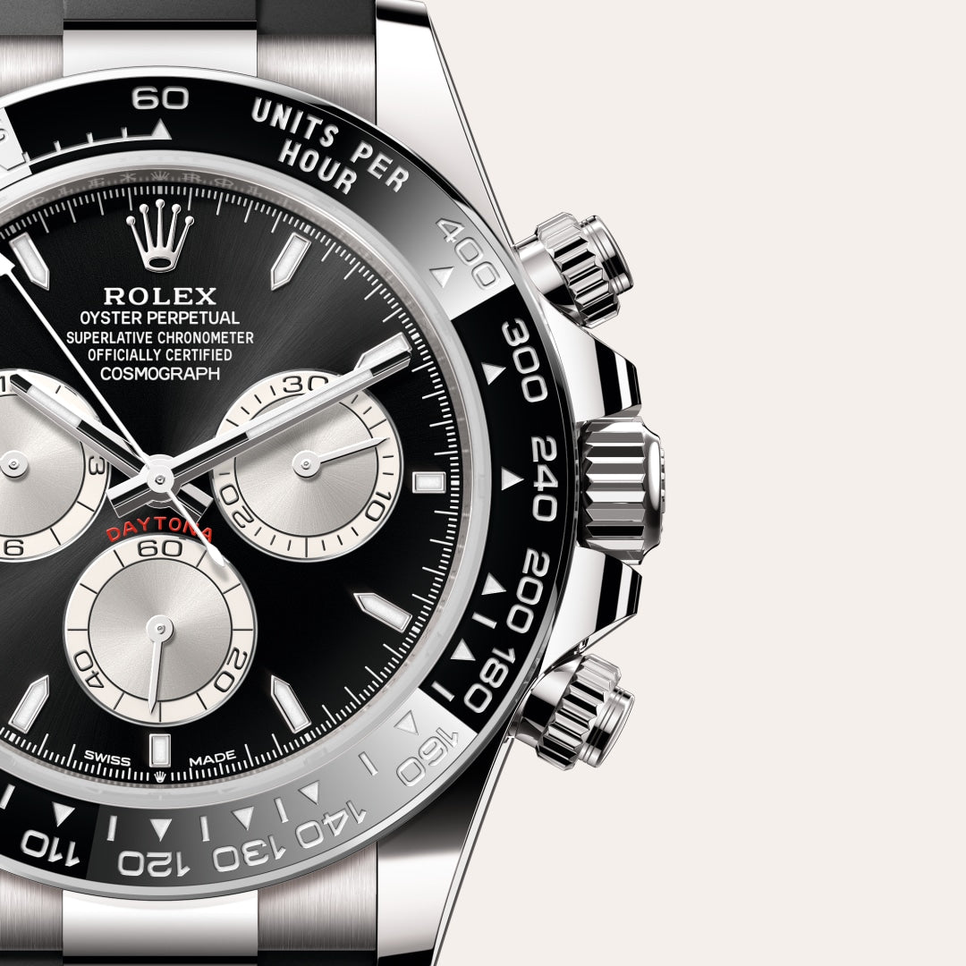 Close-up of a Rolex Daytona watch with a black dial, silver subdials, and stainless steel bezel.