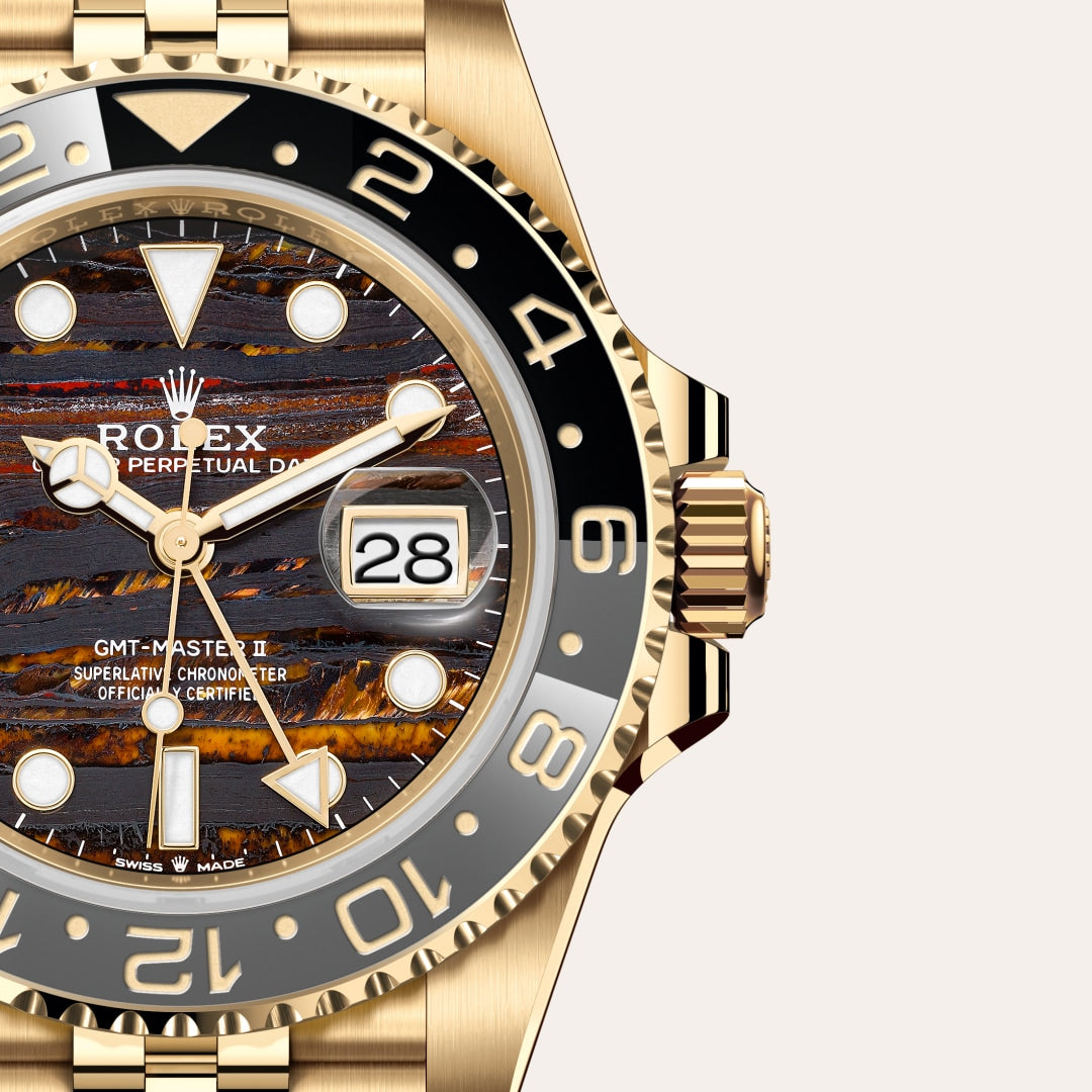 Close-up of a gold Rolex GMT-Master II watch with a textured, multicolored dial and date display.