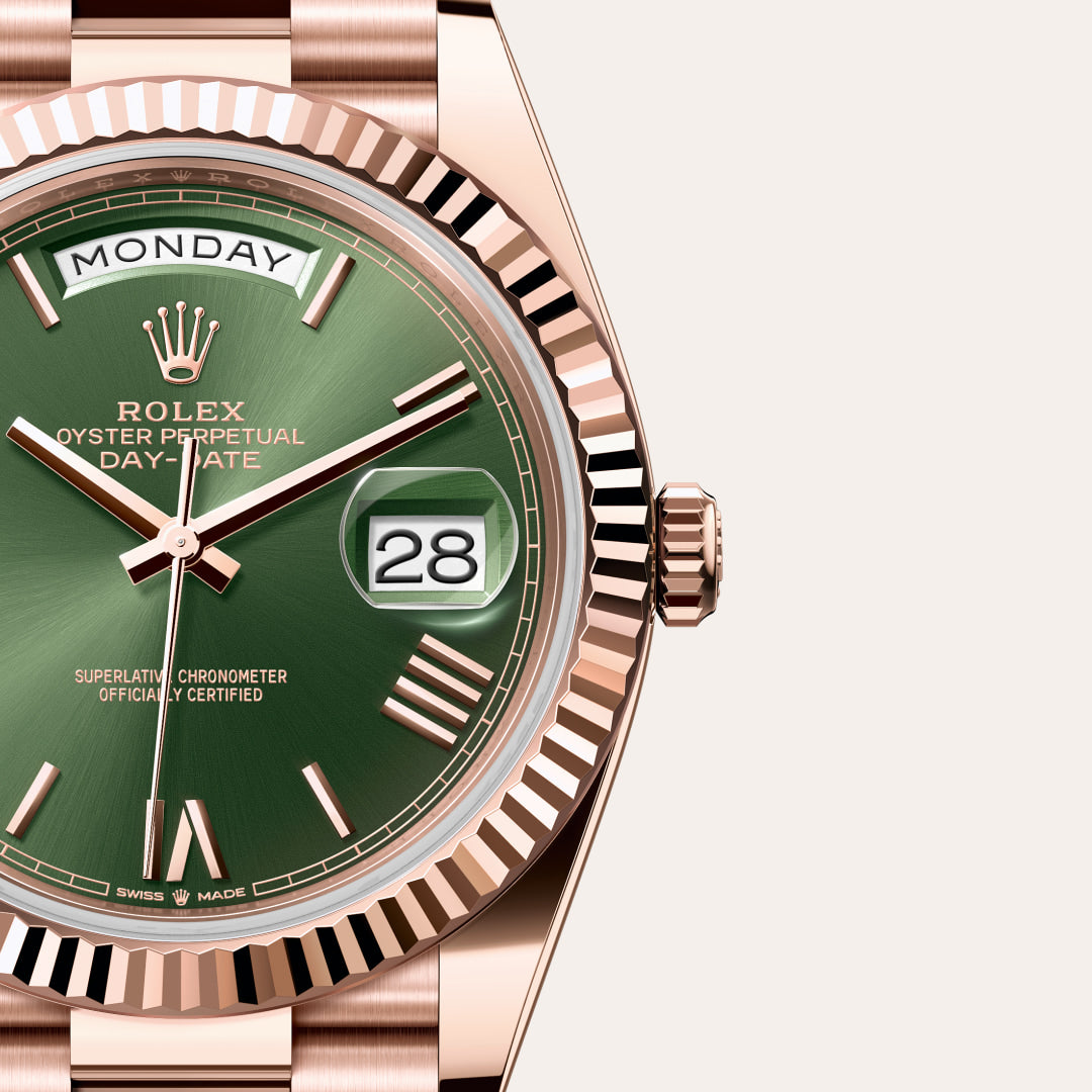 Close-up of a Rolex Day-Date watch with a green dial, gold case, and the day and date displayed.