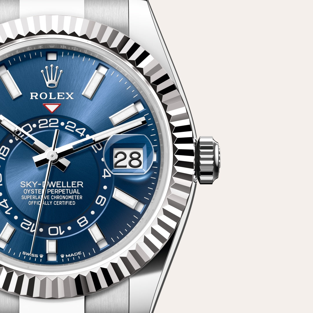 Close-up of a Rolex Sky-Dweller watch with a blue dial and silver bezel, showing the date and 24-hour hand.