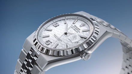 Silver Rolex wristwatch with a textured white dial against a blue gradient background.