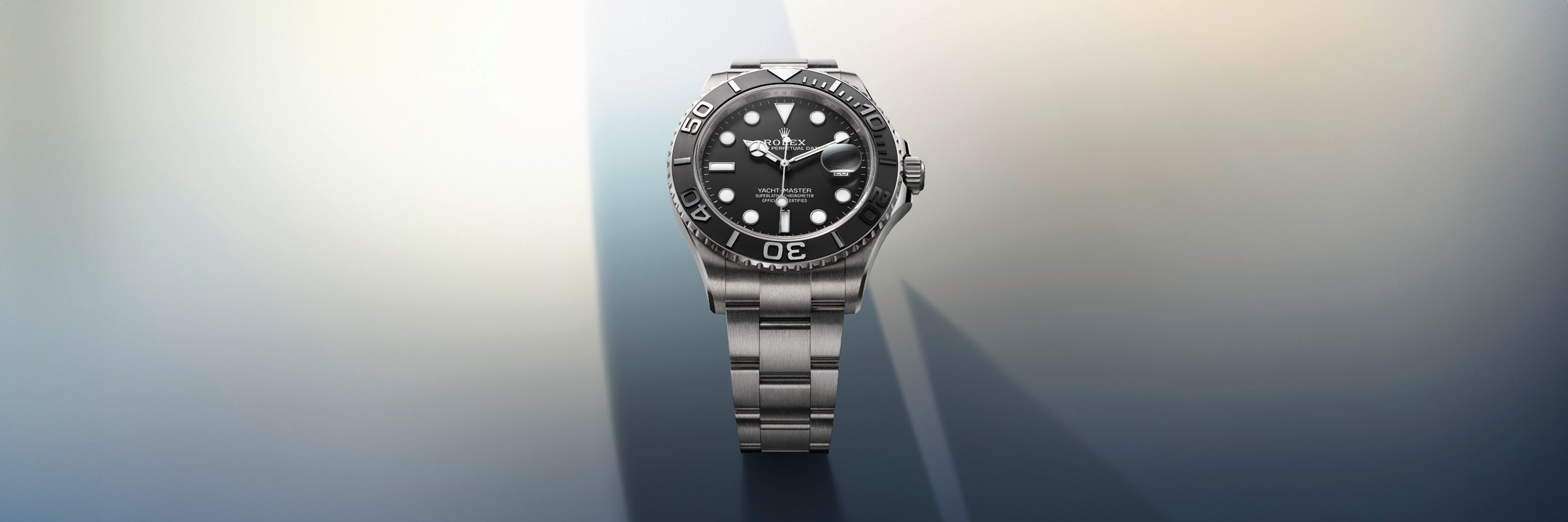 A stainless steel wristwatch with a black dial and bezel, displayed on a gradient background with light and shadow.