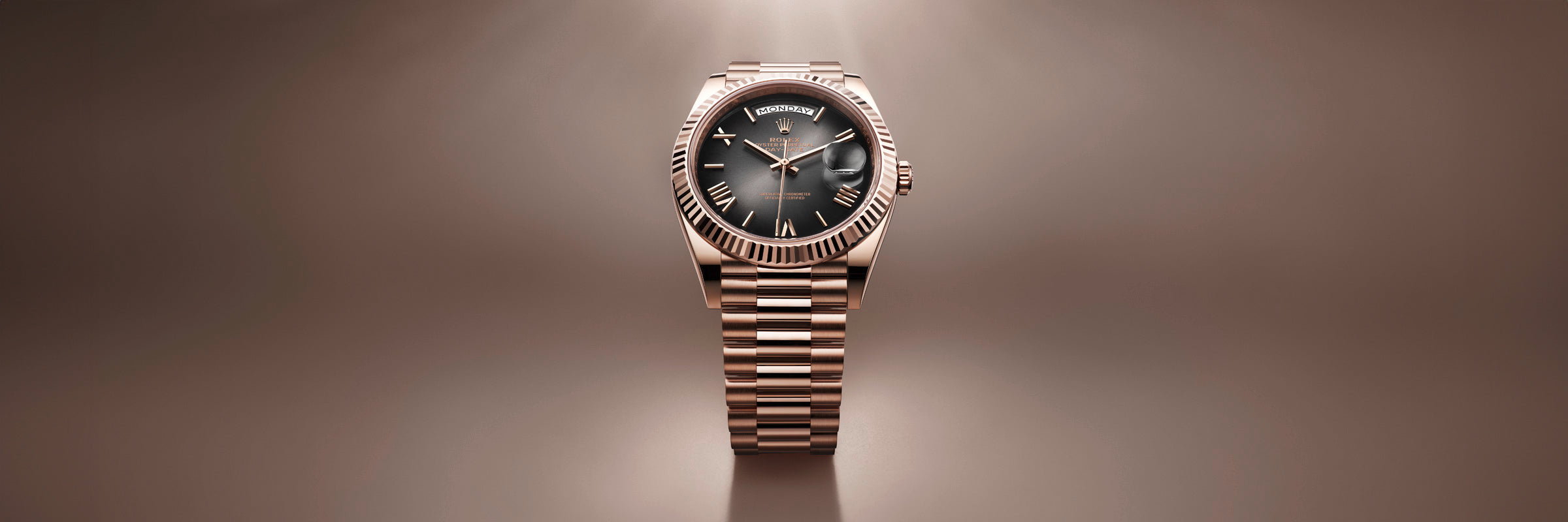 A gold wristwatch with a black face and roman numerals, displayed on a brown gradient background.