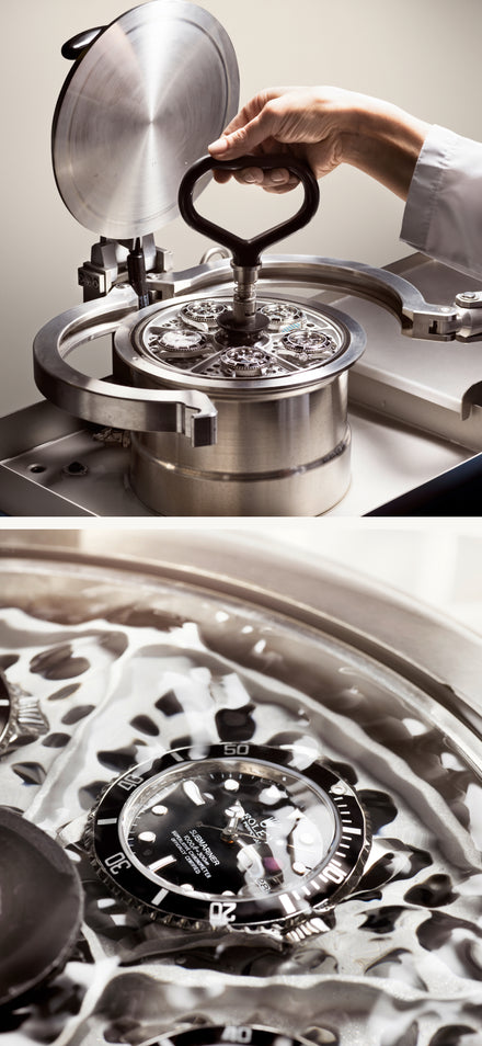 A hand operating a machine tests a black dive watch for water resistance under pressure.