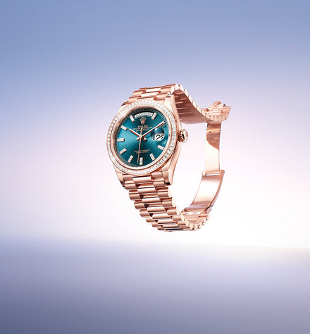 A rose gold wristwatch with a blue face and diamond bezel on a gradient light blue background.