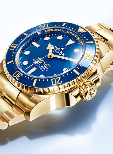 Gold Rolex watch with a blue dial and bezel, showcasing its elegant design and detailed craftsmanship.