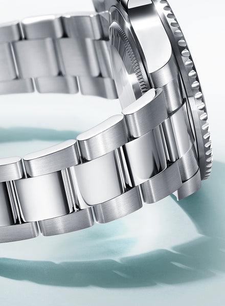 Close-up of a silver metal watch bracelet and case with polished and brushed links.